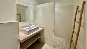 Une salle de bain moderne avec un lavabo rectangulaire, un miroir et un espace douche.