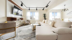 Una sala de estar moderna con un televisor de pantalla plana grande, un sofá, una mesa de centro y una zona de comedor con una mesa de vidrio.
