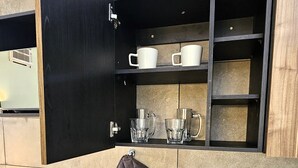 A modern kitchen with a built-in coffee maker, a kettle, and a kettle holder on the counter. - A30 Plaza Acequia Suite Black Plus   (Cuautitlán Izcalli)