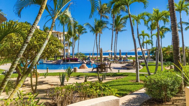 Ein Resort mit Pool, Palmen und Blick auf den Ozean.