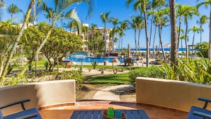 Ein Poolbereich mit Palmen, einem Pool und einer Lounge mit Tisch und Stühlen.