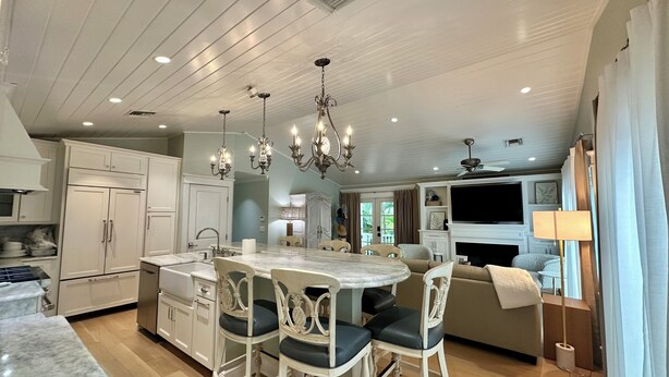 A spacious kitchen with white cabinetry, a marble island, and modern lighting fixtures. - Sea Glass Cottage North End Of Anna Maria• 2bed/2 bath w/ pool Steps to Beach (Anna Maria)