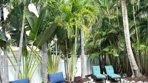 A poolside area with lounge chairs and a wooden deck. - Sea Glass Cottage North End Of Anna Maria• 2bed/2 bath w/ pool Steps to Beach (Anna Maria)
