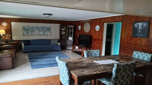 Una sala de estar con sofá, televisor, mesa de comedor y sillas.