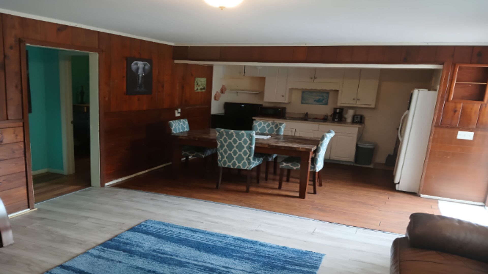 A compact living space with a dining area, kitchen, and a door leading to another room.