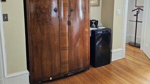 Une pièce avec une armoire en bois, une valise noire, un tapis à motifs et une porte donnant sur une autre pièce.