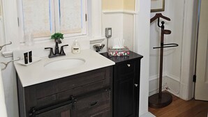 Une salle de bain avec un lavabo blanc, un meuble-lavabo en bois foncé et un miroir orné de verre décoratif.