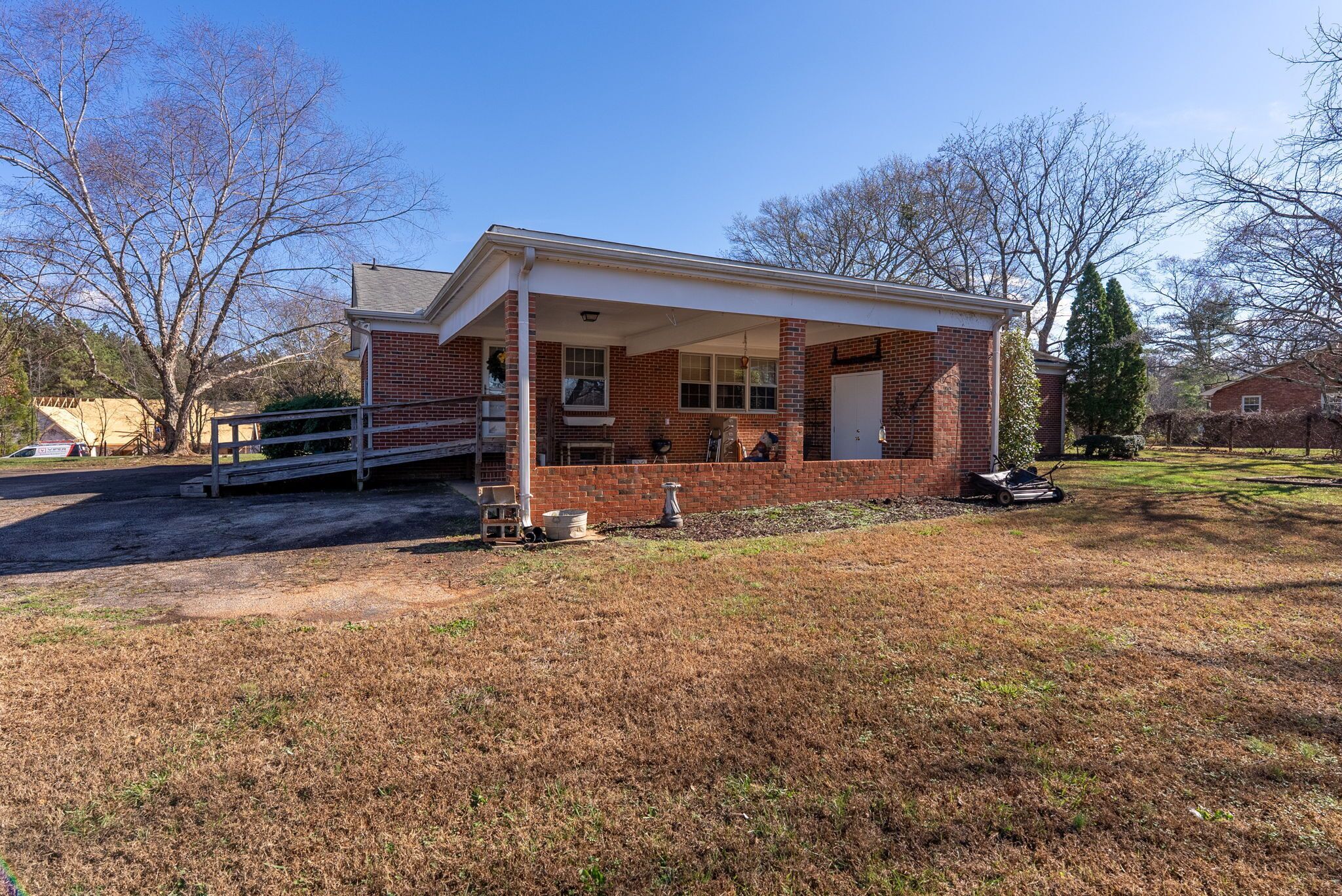 A single-story brick house with a covered porch, a garage, and a lawn.