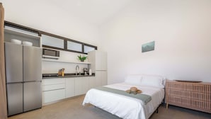 Habitació petita i funcional amb llit, taula de nit i un petit espai de cuina.