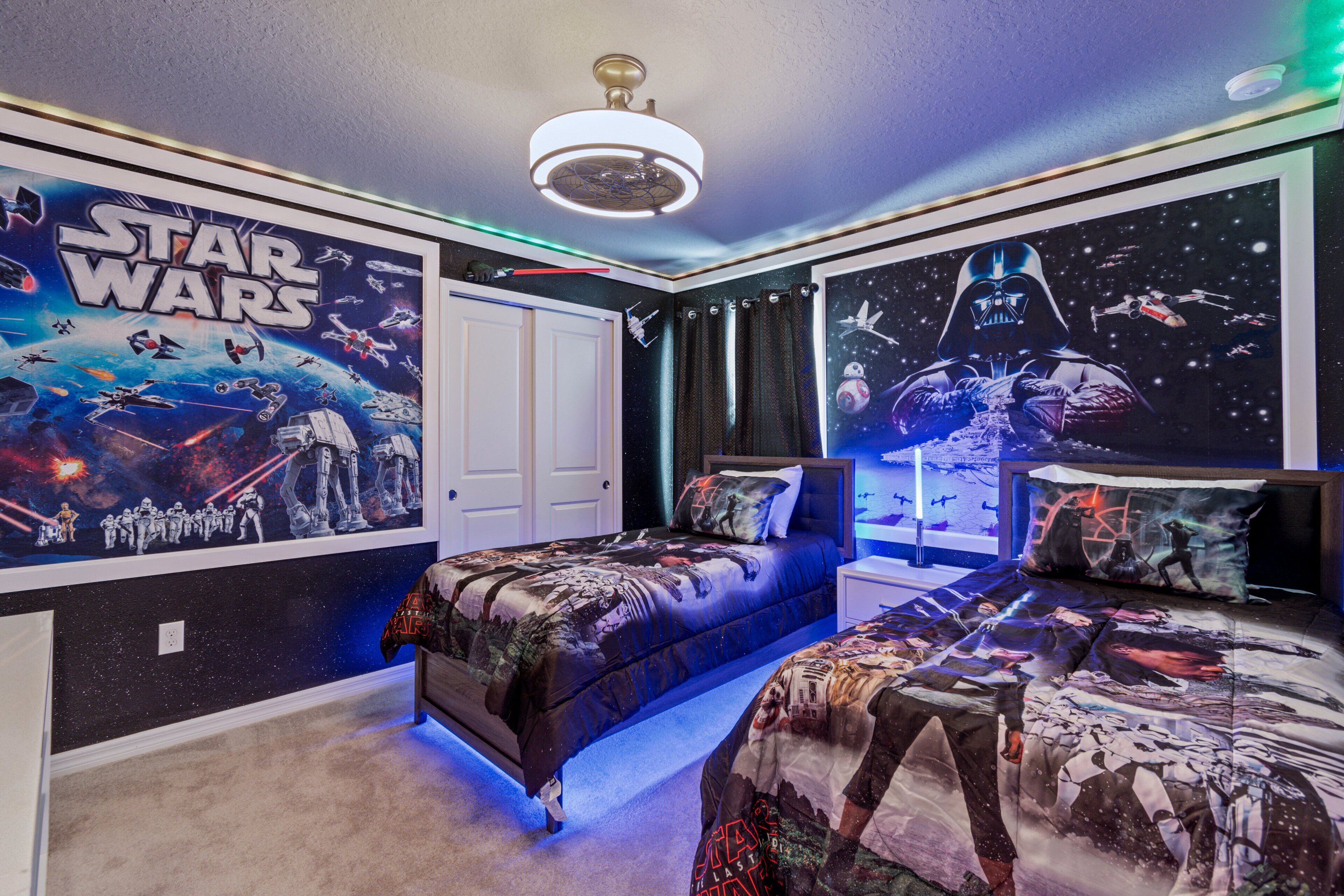 Ett sovrum med Star Wars-tema, med två sängar, en takfläkt och väggdekorationer med rymdtema.