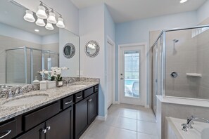 A modern bathroom with a glass shower enclosure, a large vanity with a granite countertop, and a double sink. - 2207LC- Spacious 7-bedroom home in Davenport, perfect for large groups near attractions! (Davenport)