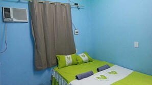 Une chambre à coucher avec un lit, des rideaux, un appareil de climatisation et un luminaire au plafond.