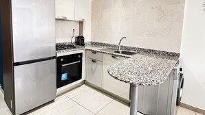 Een moderne keuken met een roestvrijstalen koelkast, een dubbele oven, een granieten aanrechtblad en een spoelbak.