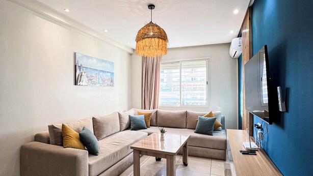 Een moderne woonkamer met een modulaire bank, een salontafel en een aan de muur bevestigde televisie.