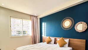 Een slaapkamer met een groot bed, een nachtkastje, twee spiegelwanden en een raam met gordijnen.