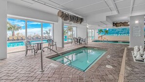 Un área de piscina interior con vistas a la ciudad, sillones de descanso y mesa de billar.