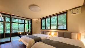 A hotel room with two beds, large windows, a ceiling light, and a wall-mounted air conditioning unit.