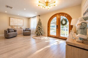 Ein geräumiges Wohnzimmer mit Holzboden, einem Weihnachtsbaum und einem großen, bogenförmigen Durchgang.
