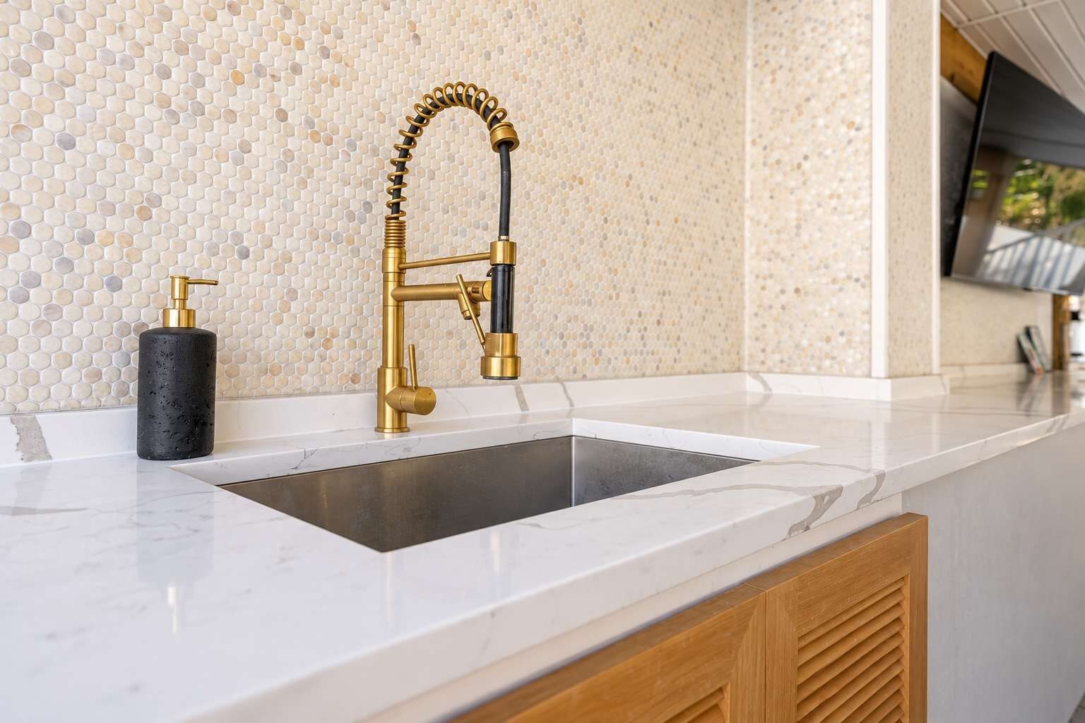 A kitchen with a modern faucet, a soap dispenser, and a tiled backsplash.