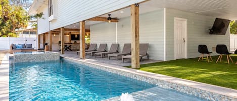 Piscina con borde de azulejos, sillas de descanso y zona ajardinada.