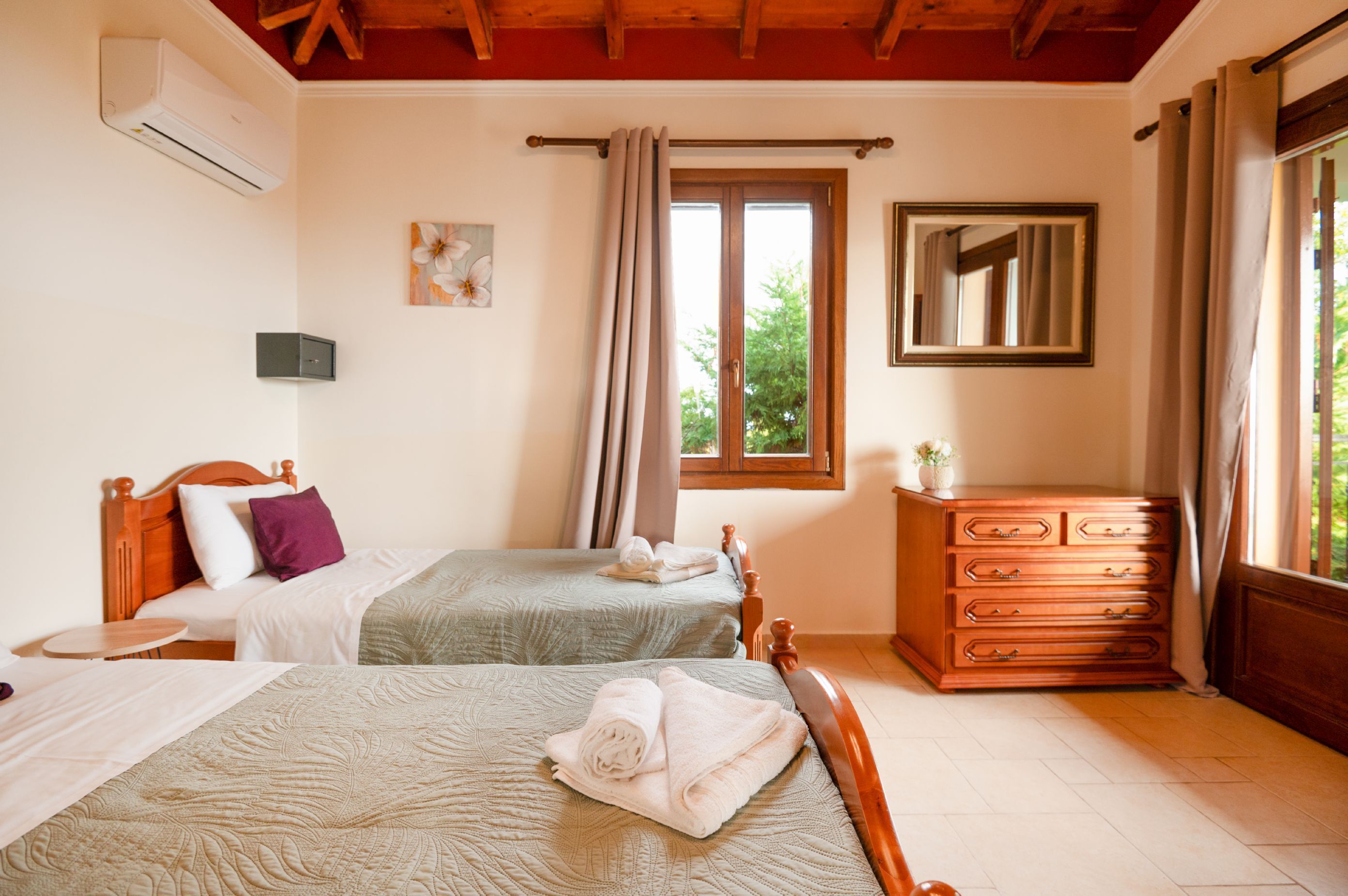 A bedroom with two beds, a wooden dresser, a mirror, and a window with curtains.