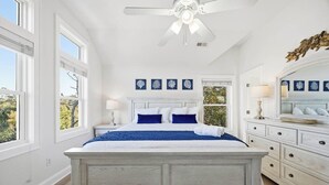 Ein Schlafzimmer mit einem großen Bett, weißen Wänden und einem Deckenventilator.