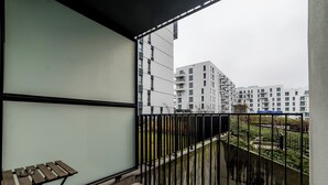 En balkon med udsigt til moderne lejlighedskomplekser, et lille bord med en skål og en gelænder.