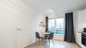 Et moderne køkken med spiseplads, hvide skabe og et vindue med gardiner.