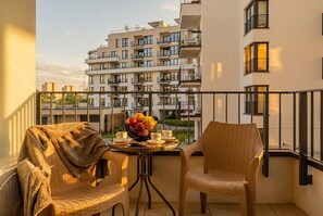 A balcony with wicker chairs, a table with a fruit bowl, cups, and a blanket. - Pychowicka Prestigious Black&Cashmere (Kraków)