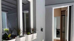 Eine moderne Wohnung mit einer grauen Au ßenwand, einem Fenster mit Blumentöpfen und Blick in den Küchenbereich.