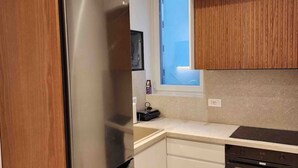 Eine moderne Küche mit Edelstahl-Kühlschrank, Einbauofen und Holzschränken.