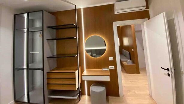 Ein modernes Schlafzimmer mit eingebautem Kleiderschrank, einem Schminktisch mit Spiegel und einer Treppe, die zu einer oberen Ebene führt.