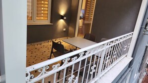 Ein Balkon mit weißer Reling, einem Tisch und Stühlen.