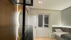 Ein modernes Schlafzimmer mit Bett, Nachttischen, einem Fernseher und einem Fenster.