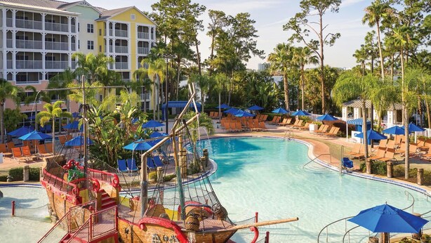 A swimming pool with a pirate ship play area, lounge chairs, and umbrellas. - Resort Getaway Ideal for Families, Disney Trips & Relaxation (Orlando)