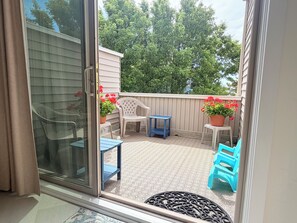 A sliding glass door leading to an outdoor patio with a white fence, potted plants, and outdoor furniture. - 4 Laurel Street # 222- Mariners Court. Perfect location! Community Pool! Downtown! (Rehoboth Beach)
