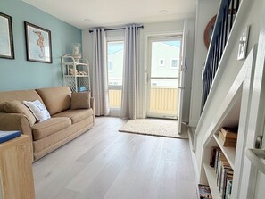 A living room with a sofa, a glass cabinet, and a staircase. - 4 Laurel Street # 222- Mariners Court. Perfect location! Community Pool! Downtown! (Rehoboth Beach)