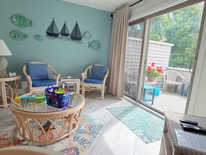 A room with wicker furniture, a glass table, and a view of the outdoors. - 4 Laurel Street # 222- Mariners Court. Perfect location! Community Pool! Downtown! (Rehoboth Beach)