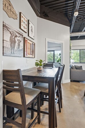 A dining area with a wooden table, chairs, and a potted plant. - 1BR Condo - King Bed - 10mins to Broadway (Nashville)