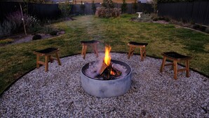 A circular fire pit with seating around it, surrounded by gravel. - Birchfrost cottage | Quintessential cosy | Central Orange (Orange)