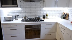 A kitchen with white cabinets, a microwave, a gas stove, and a dishwasher. - Birchfrost cottage | Quintessential cosy | Central Orange (Orange)