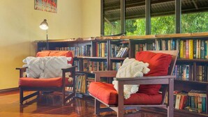 Un rincón acogedor para leer con dos sillas de madera, una lámpara y estanterías llenas de libros.