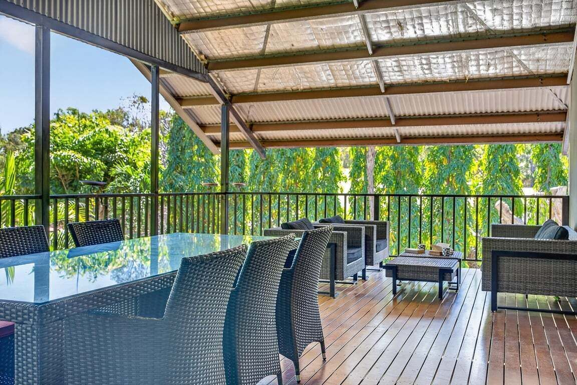 An outdoor deck with a glass-top table, wicker chairs, and a sofa.