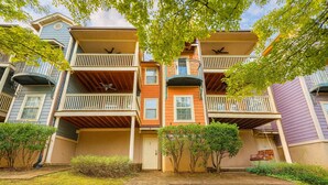 Un edificio residencial de varios pisos con balcones, una entrada principal y un pequeño jardín delantero.