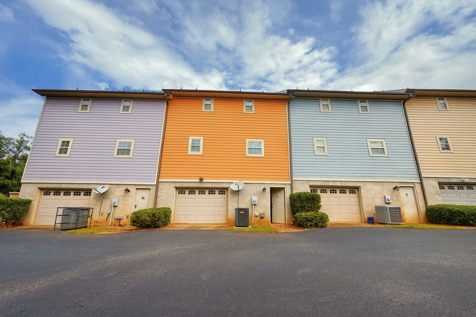 A row of townhouses with individual garage doors and satellite dishes.