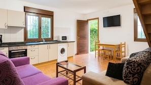 Un espacio habitable compacto con kitchenette, comedor y sofá.