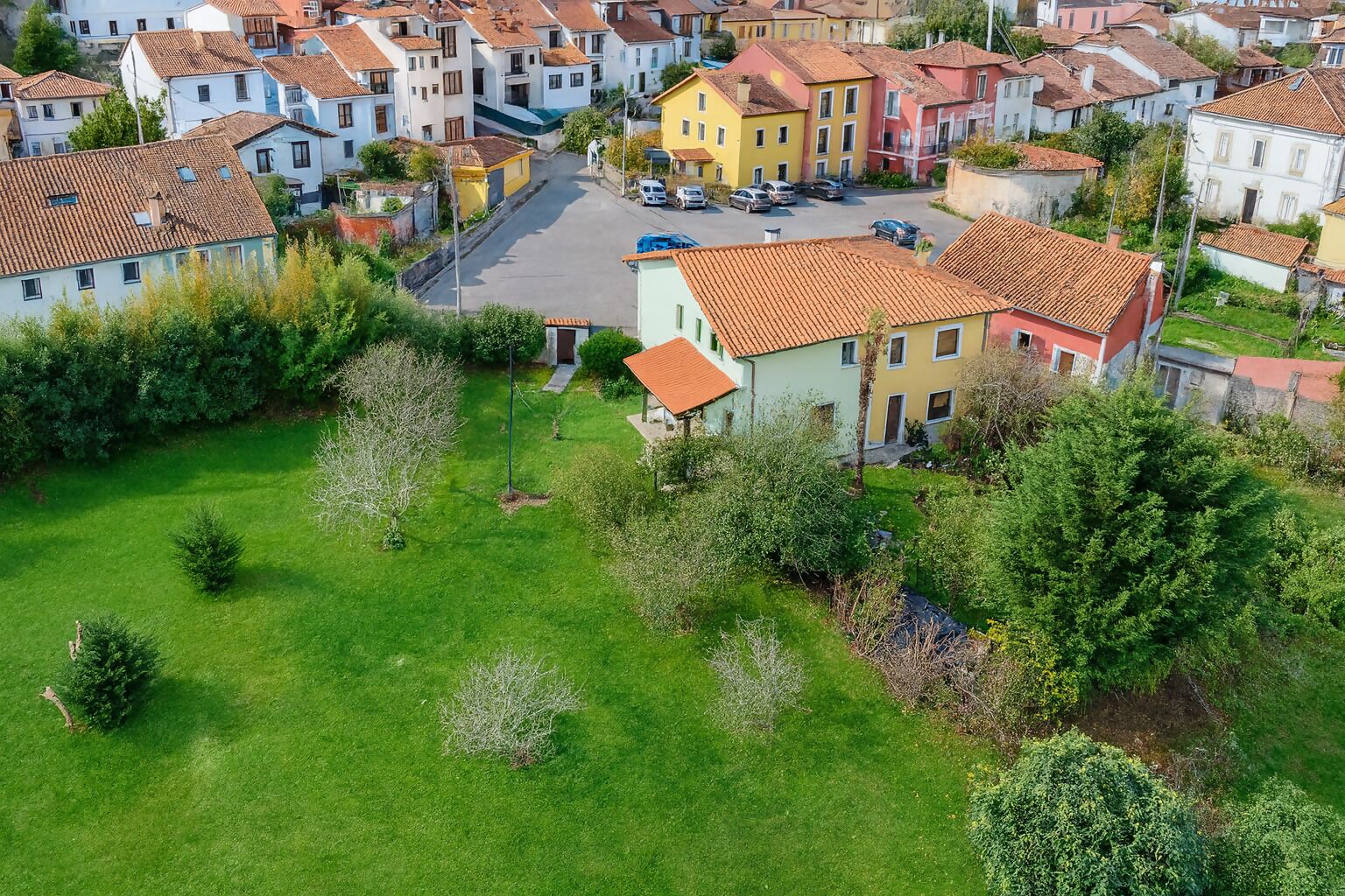 An aerial view of a residential area with houses, a green lawn, and a clear sky.