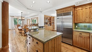 Una cocina amplia con armarios de madera, un refrigerador de acero inoxidable y una isla de granito.
