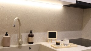 Una cocina moderna con un lavamanos grande, un grifo y un pequeño taburete de madera con una pizarra.
