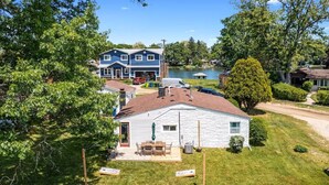 A single-story house with a front porch, a small deck, and a yard. - Modern & Clean Waterfront Retreat - Beach, Fire Pit, Pet friendly, Getaway (White Lake)